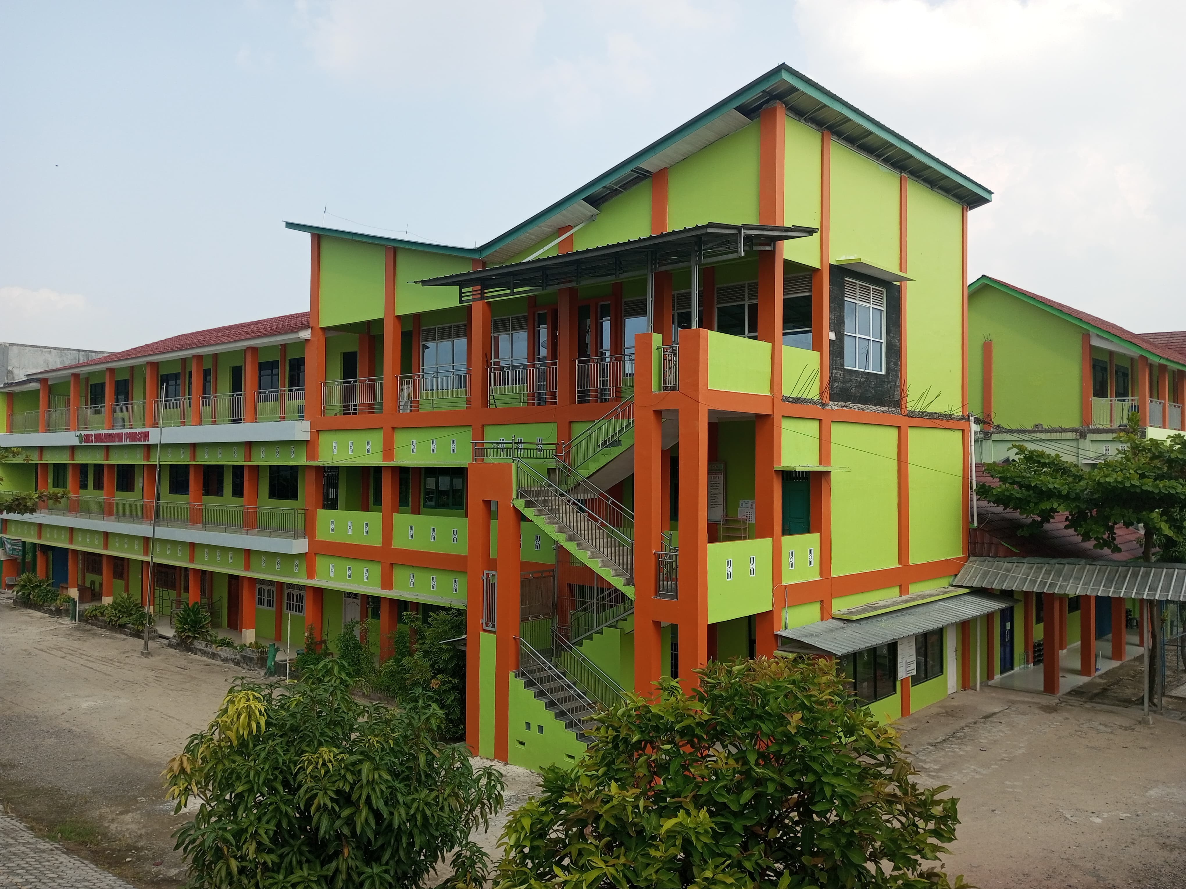 Gedung sekolah dengan arsitektur modern dan taman hijau